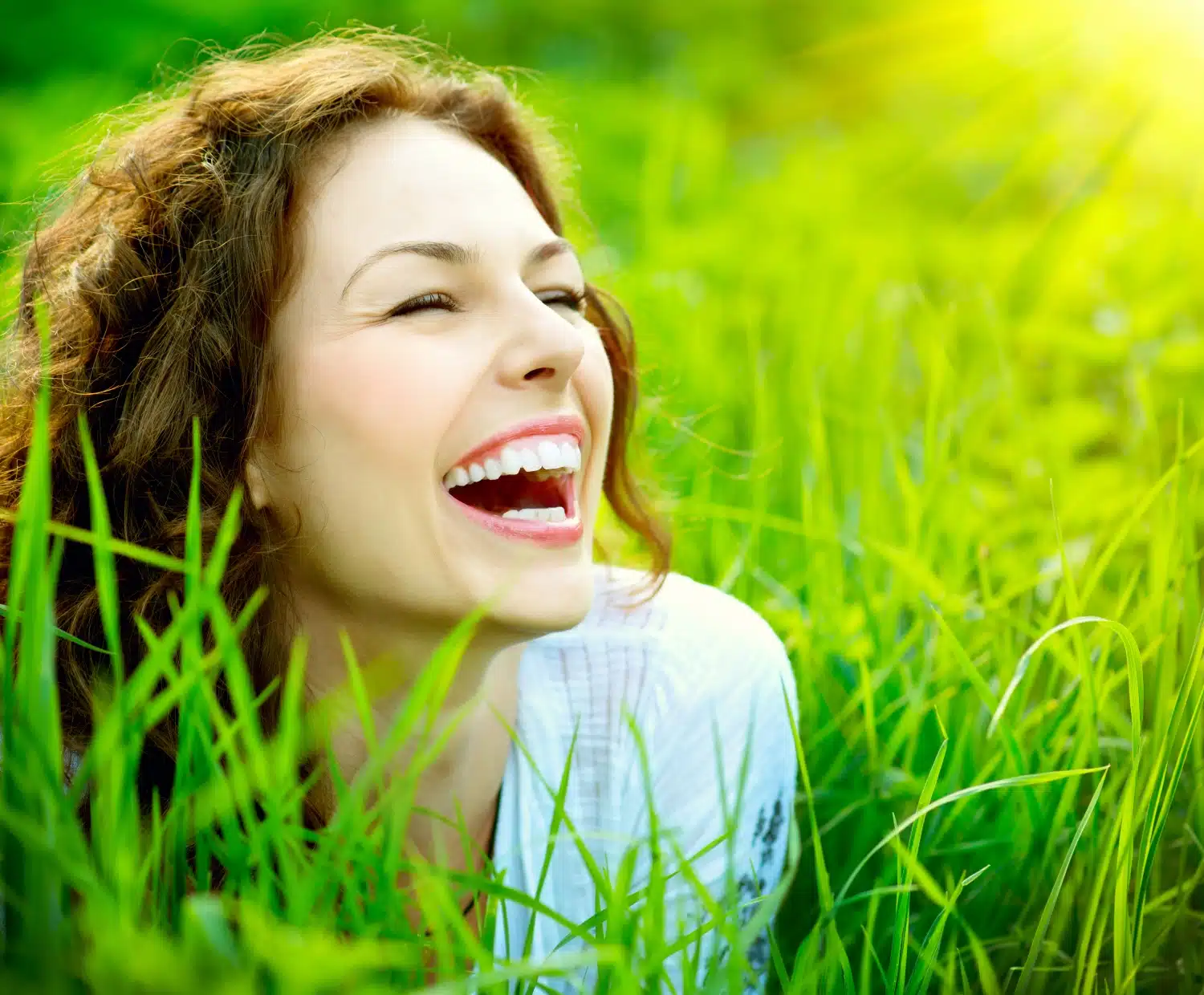 Woman smiling, looking right, lying face down in the deep grass. She’s ecstatically laughing at something. health coaching United States remote, health coaching remote USA, health coaching Colorado, health coaching Loveland Colorado, health coach United States remote, health coach remote USA, health coach Colorado, health coach Loveland Colorado